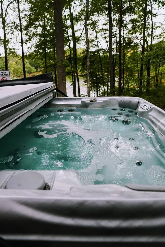 Six-person hot tub glowing on the deck at dusk beneath string lights