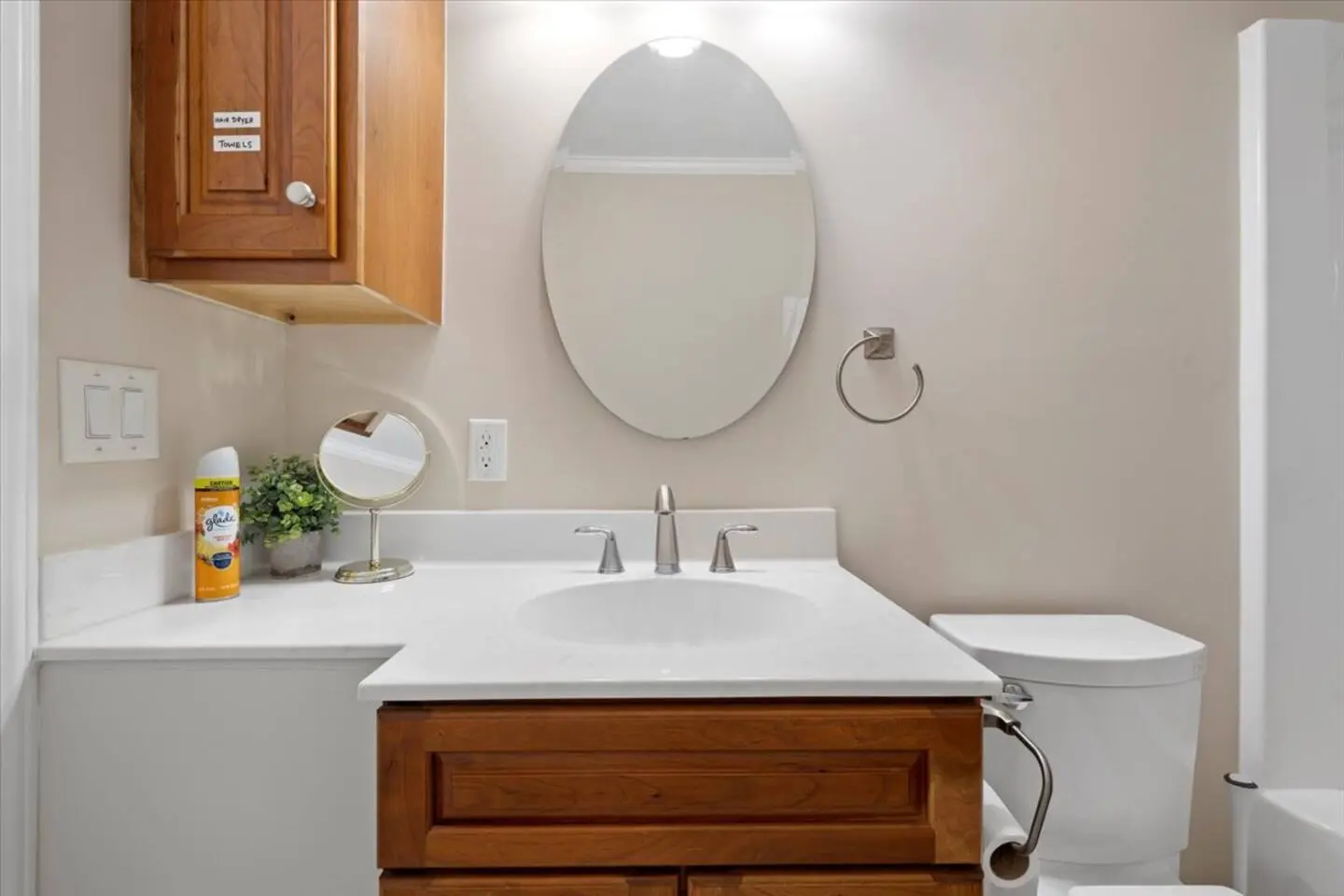Bathroom with a wood vanity, oval mirror, and a tub