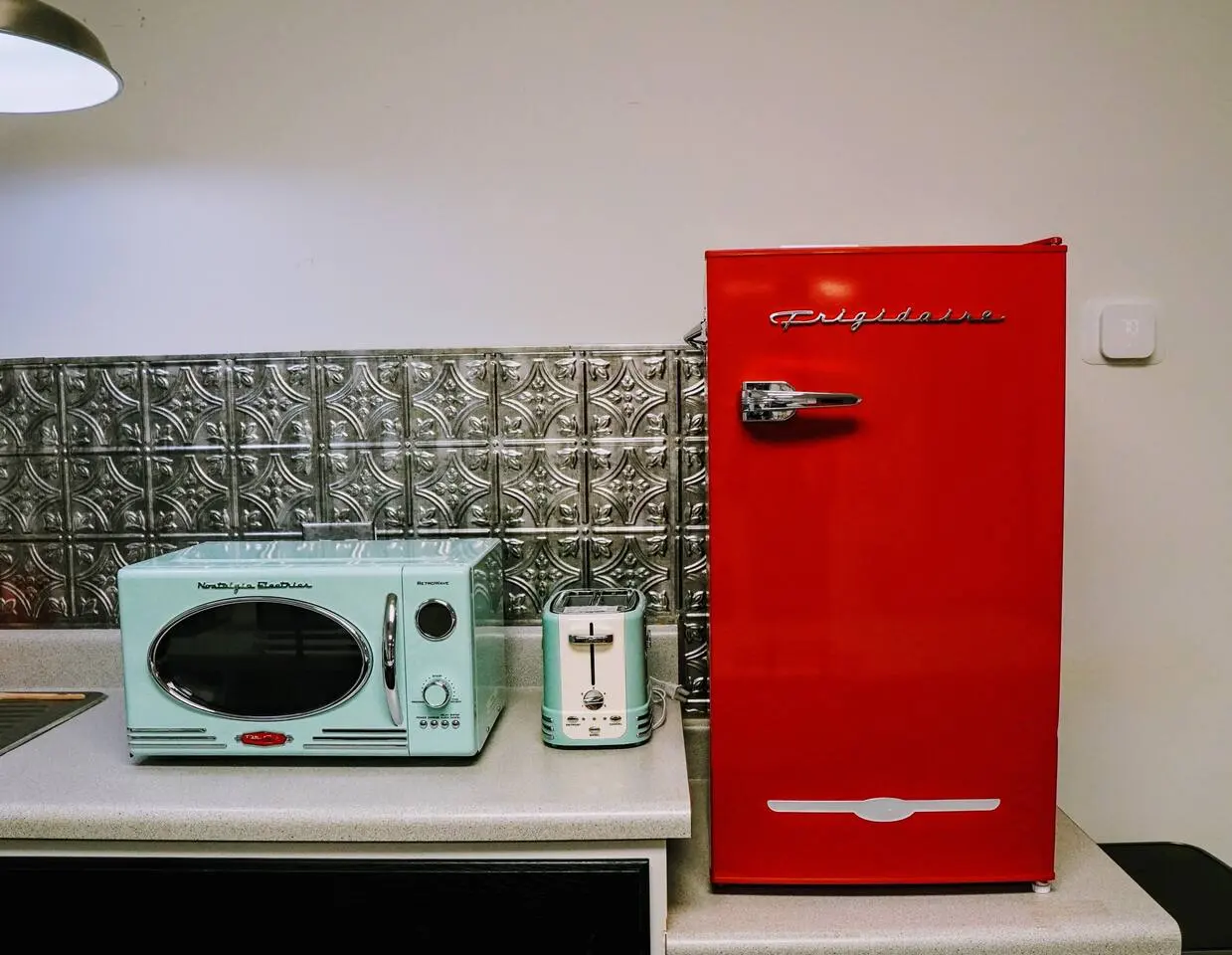Basement kitchenette with a retro red fridge, mint microwave, and toaster