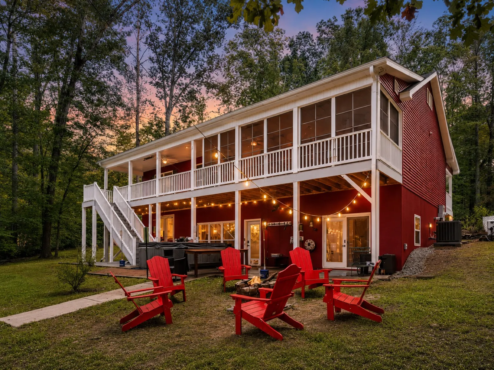 The red lake house at Pointe Mayo Lake with a wraparound deck, fire pit, and red Adirondack chairs at the water's edge